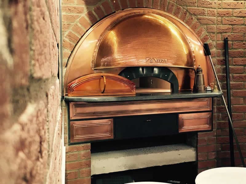 Four à pizza en cuivre dans une voûte de briques